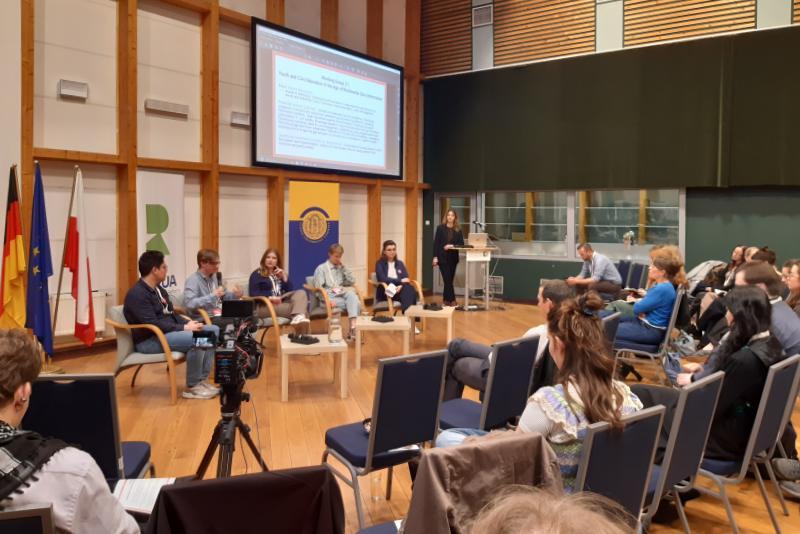 Grupa studentów i wykładowców słucha prezentacji podczas warsztatów na konferencji