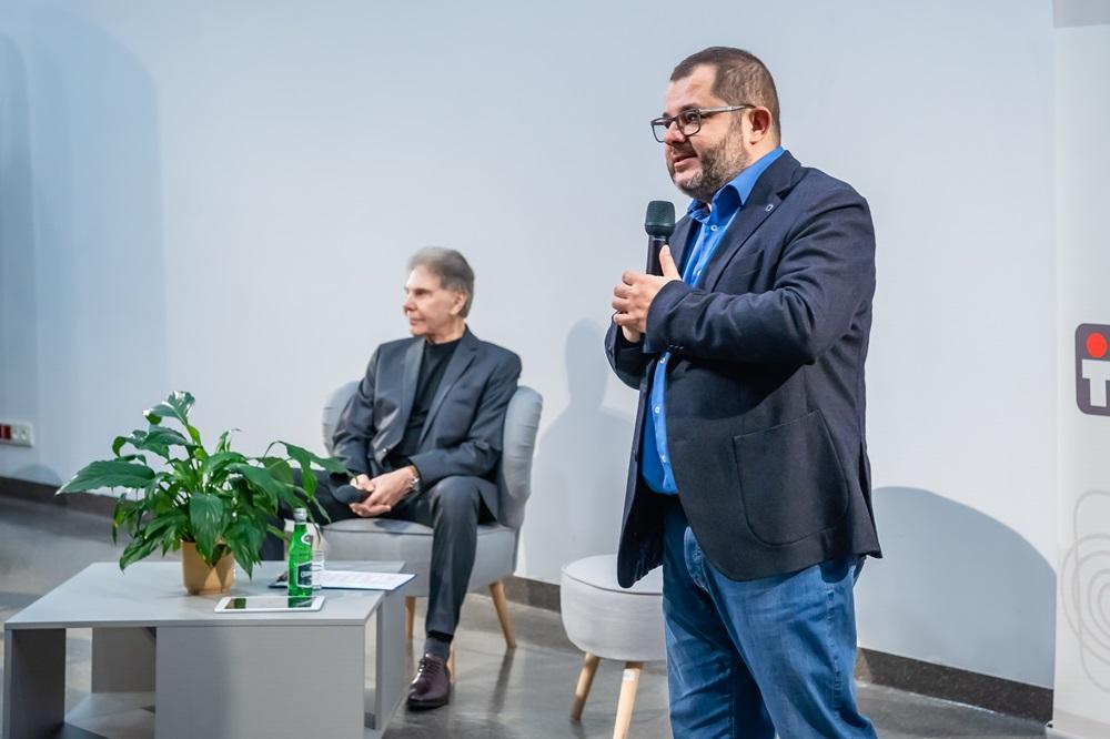 Zdjęcie panelu, na pierwszym plane stoi profesor Tomasz Grzyb z mikrofonem, w tle siedzi profesor Cialdini