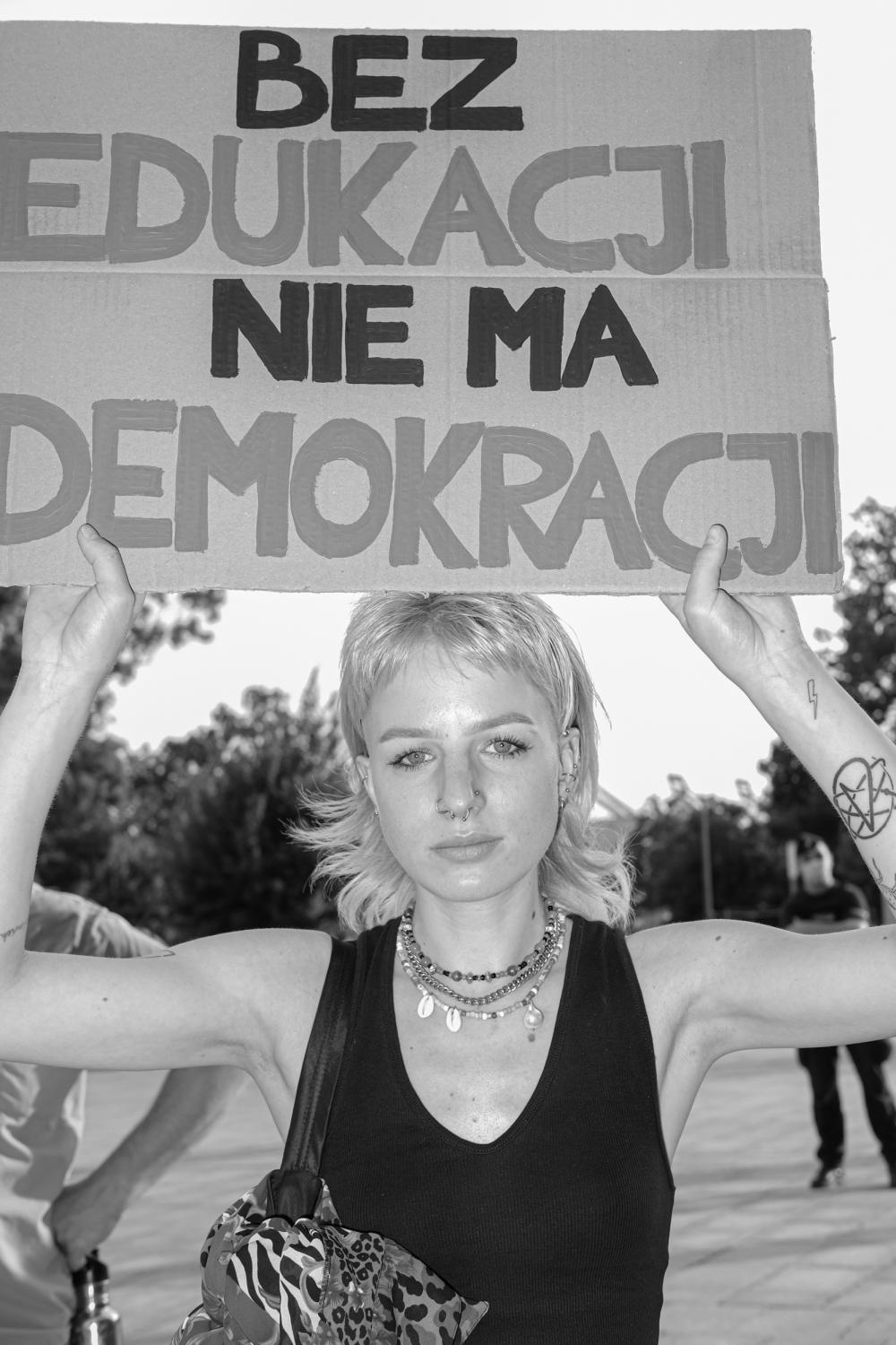 Dziewczyna trzyma transparent z napisem: Nie ma edukacji bez demokracji