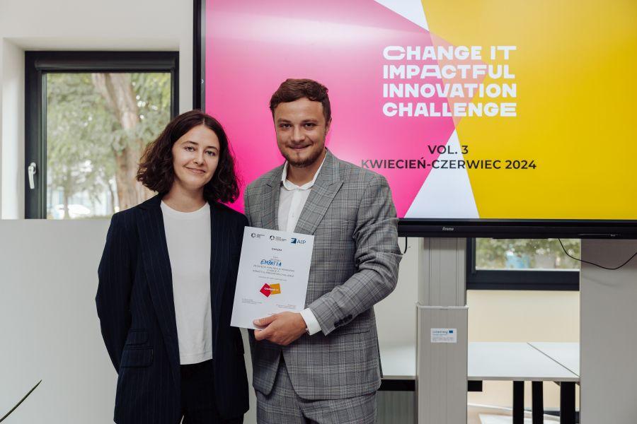 Dwoje członków zespołu Empatia na tle prezentacji z napisem „CHANGE IT – IMPACTFUL INNOVATION CHALLENGE. VOL. 3. KWIECIEŃ–CZERWIEC 2024