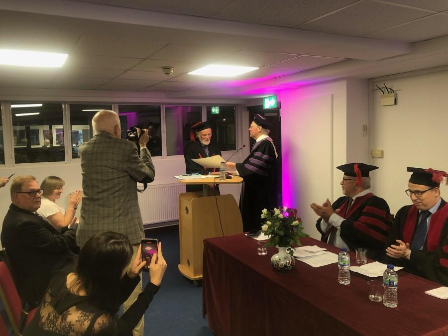 Profesor doktor habilitowany Paweł Boski odbiera dyplom doktora honoris causa. Uczestnicy uroczystości biją brawo i robią zdjęcia