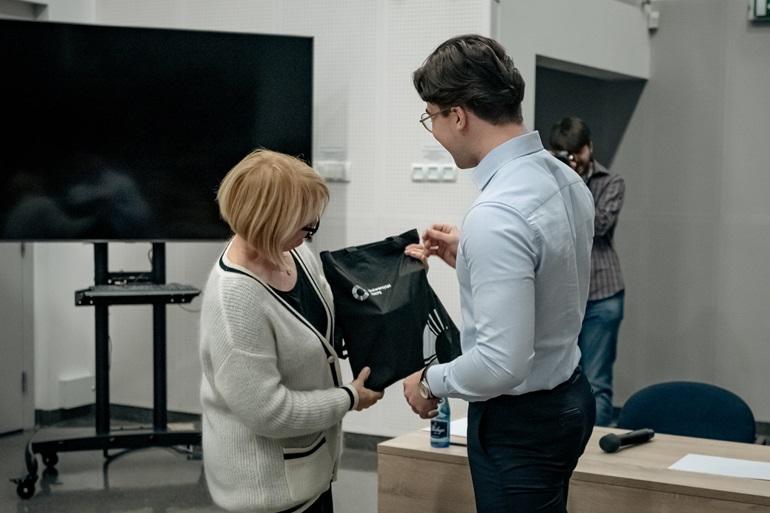 Monika Lewandowicz-Machnikowska wręcza torbę z logiem SWPS laureatowi konkursu