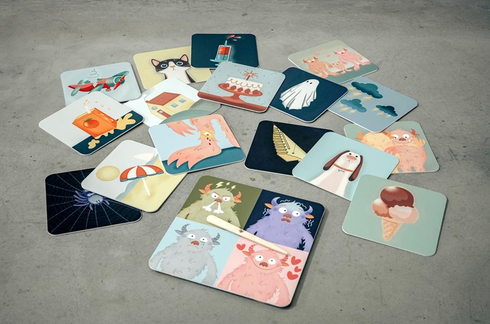 Karty edukacyjne przedstawiające różne, rysunkowe grafiki, takie jak kolorowe potwory obrazujące różne emocje, psa, lody, plażę, duchy