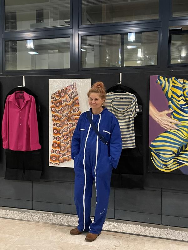 Kobieta na tle prac na wystawie "Pomiędzy" na Uniwersytecie SWPS w Krakowie