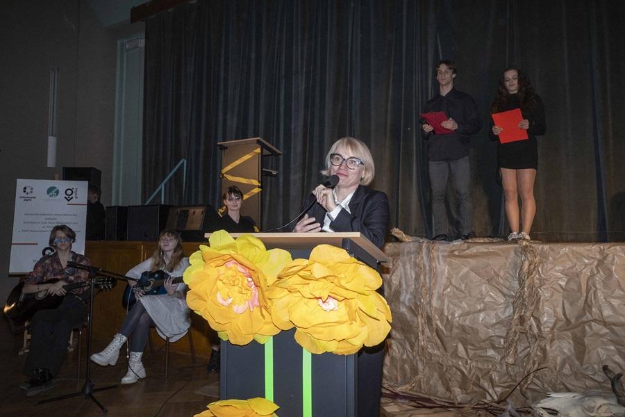 dr hab. Monika Lewandowicz-Machnikowska przy mównicy ozdobionej żółtymi kwiatami