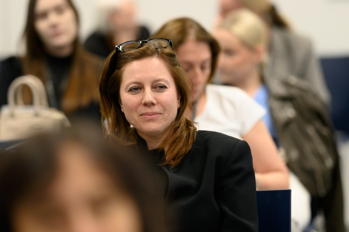 Zbliżenie na kobietę, która siedzi wśród publiczności konferencji naukowej „Innowacje społeczne. Wyzwania – Rozwiązania – Praktyki”, odbywającej się na Uniwersytecie SWPS w Warszawie