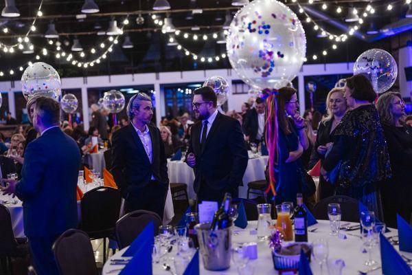 Gala Nagrody Stowarzyszenia PRom 2026. Grupa uczestniczek i uczestników Gali rozmawia w sali bankietowej, w tle widać dekoracje i stoły