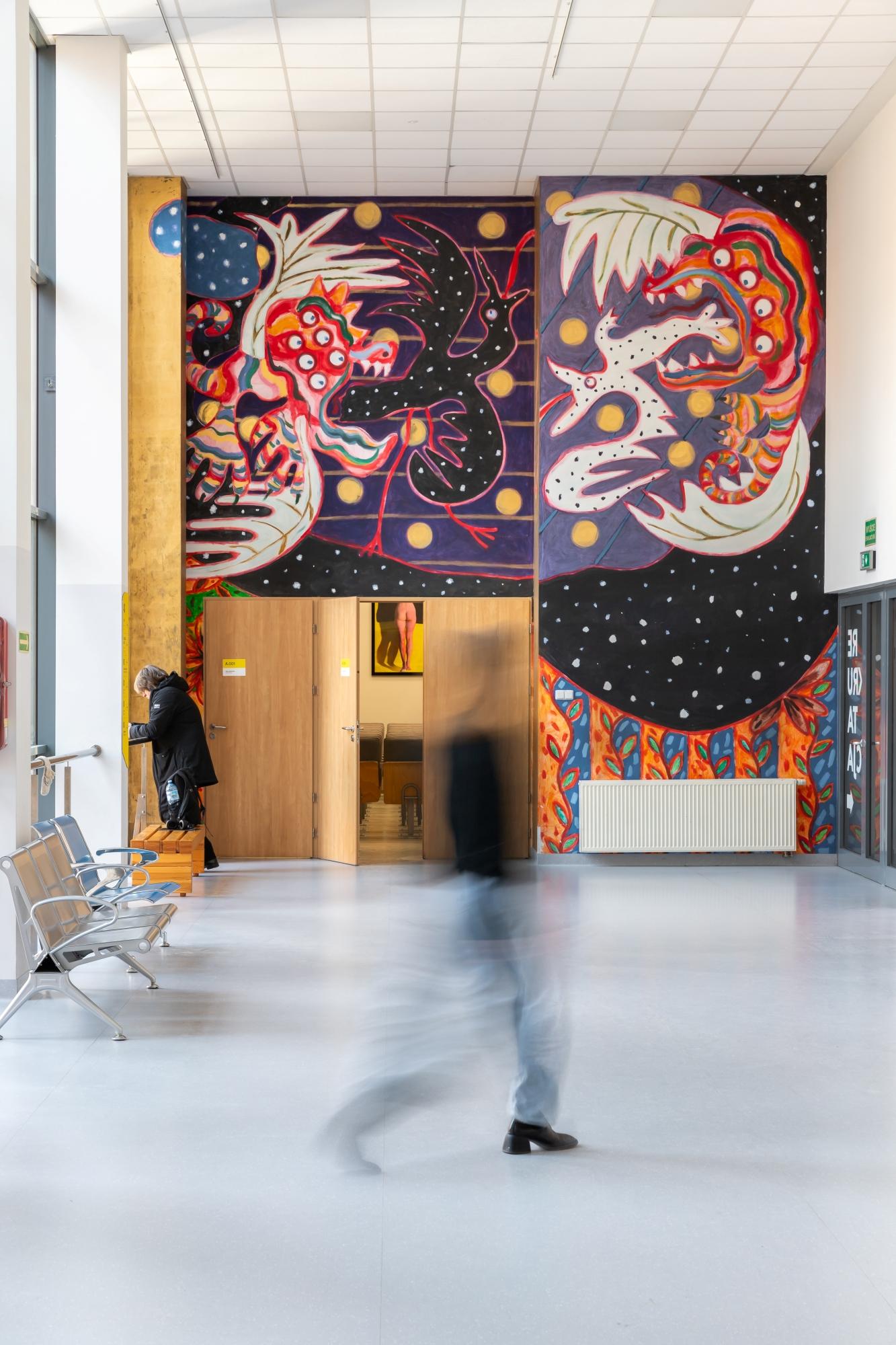Mural Mariusza Kruka na ścianie Collegium Da Vinci w Poznaniu. Przedstawia abstrakcyjne smoki pożerające stwory przypominające ptaki.